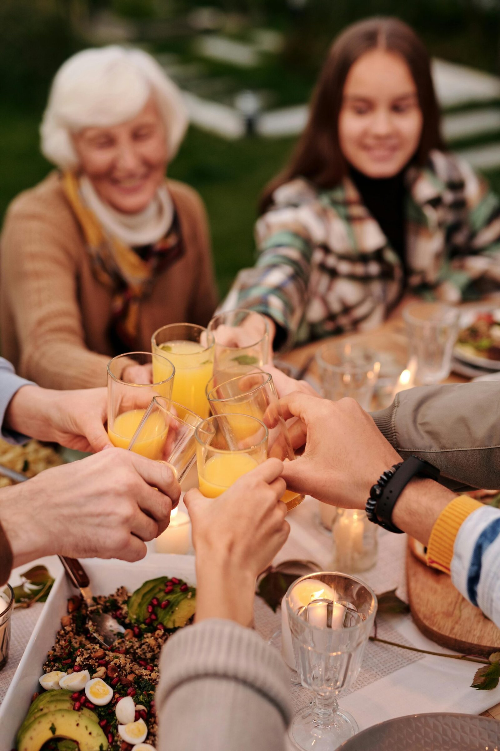 A joyful family gathering at an outdoor dinner with orange juice toasts and laughter.
